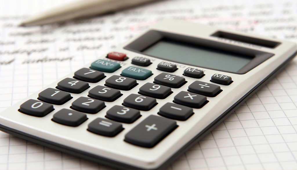 A calculator and pen on graph paper represent Advisors Management Group's fiduciary financial advisory and accounting services in Wisconsin.