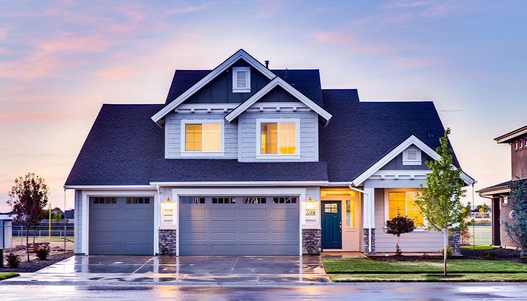 A two-story Wisconsin home with a three-car garage and lit windows at sunset, reflecting financial security and planning.