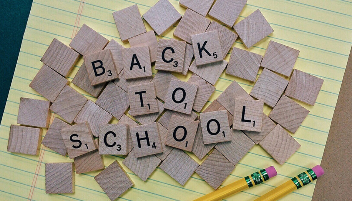 Scrabble tiles spell Back to School on a yellow notepad with two pencils, representing tax planning for Wisconsin families.