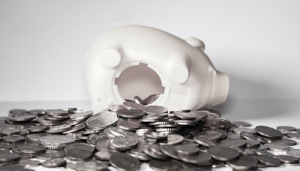 A white piggy bank lies on its side with coins spilled out, symbolizing the importance of tax planning with Wisconsin fiduciary advisors.