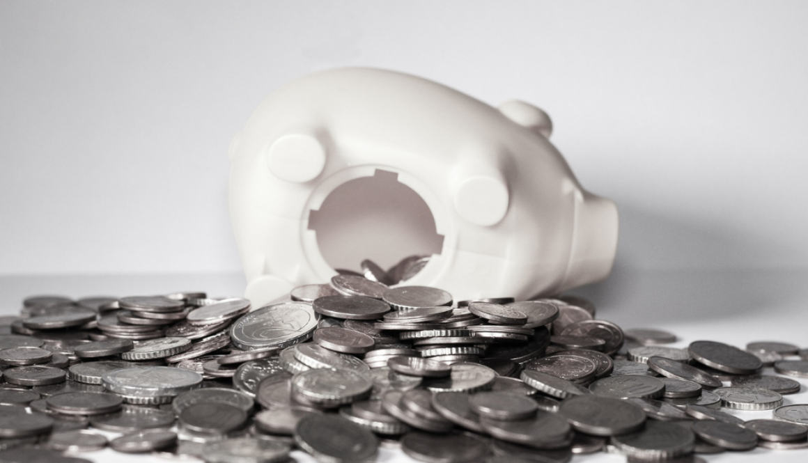 A white piggy bank lies on its side with coins spilled out, symbolizing the importance of tax planning with Wisconsin fiduciary advisors.