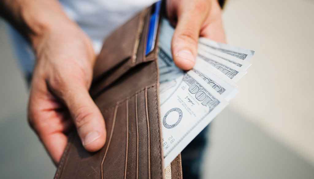 Hands holding an open wallet with hundred-dollar bills, representing smart financial planning by fiduciary advisors in Wisconsin.