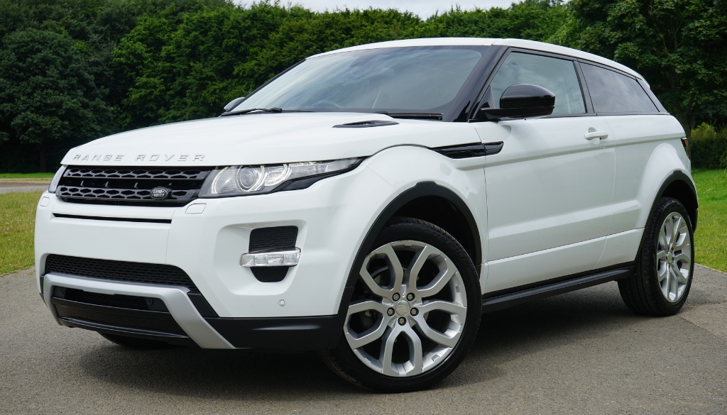 A white Range Rover Evoque SUV parked on a Wisconsin road with lush greenery and trees, near Advisors Management Group locations.