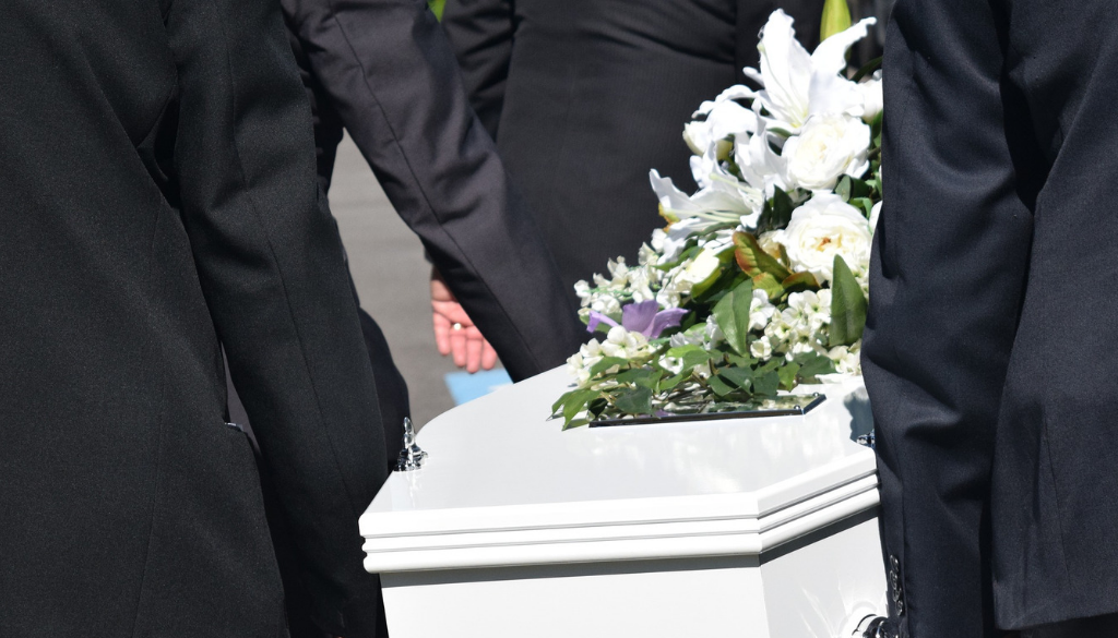 People in black attire carry a white casket adorned with flowers at a funeral in Wisconsin, home to trusted fiduciary advisors.