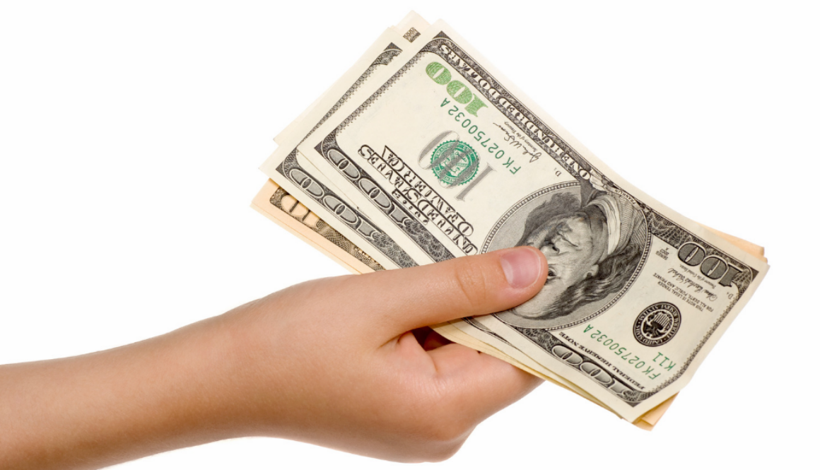A hand holds a fanned stack of $100 bills, representing financial planning by fiduciary financial advisors in Wisconsin.