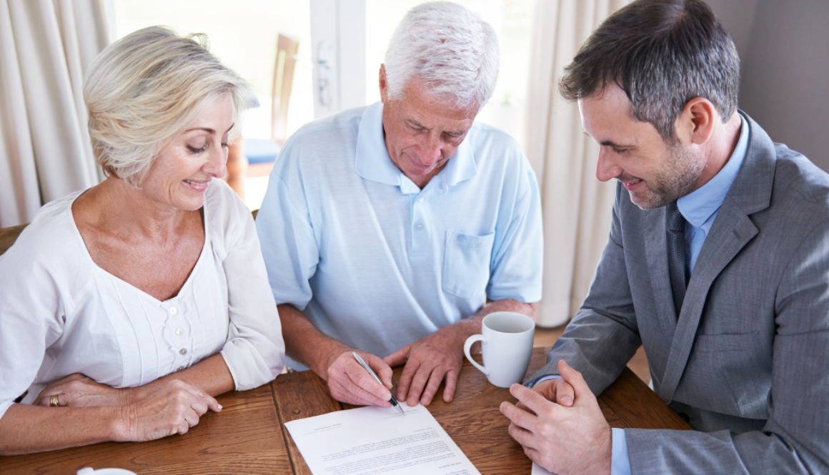 An older couple smiles while reviewing and signing documents with a fiduciary financial advisor in Wisconsin.