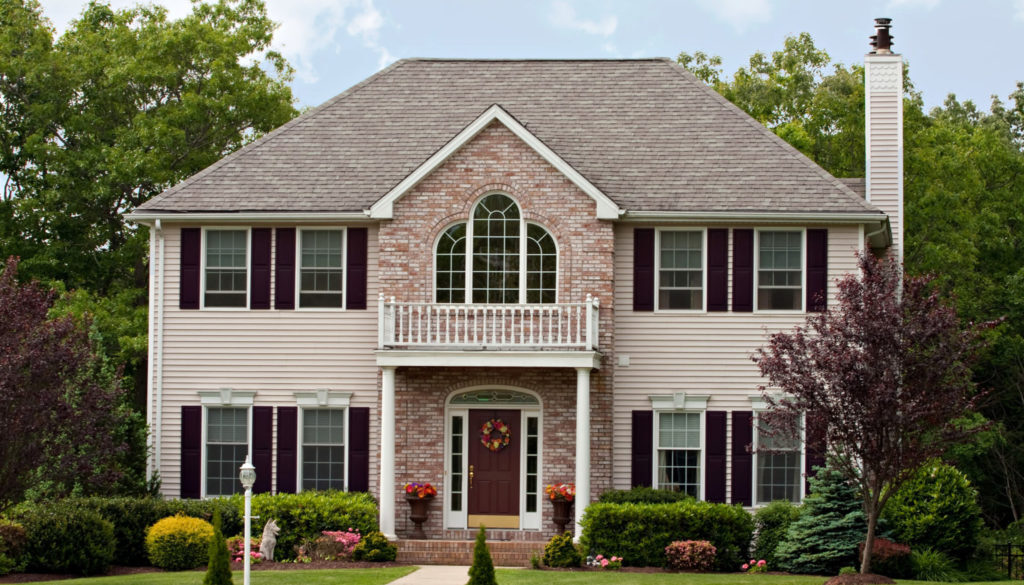 Two-story suburban home with brick and siding, front porch, and landscaped yard—ideal for Wisconsin fiduciary financial planning.