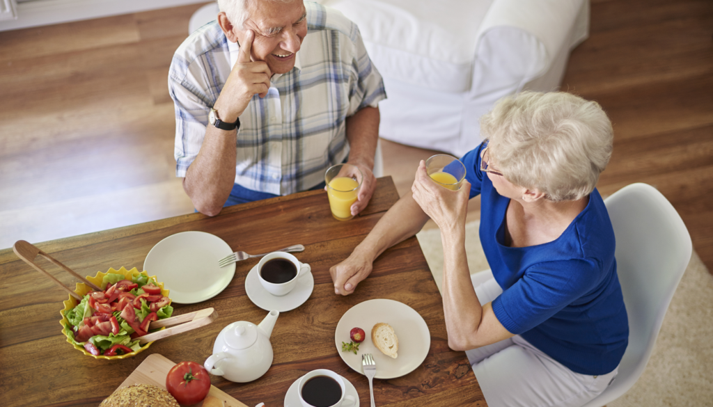 An elderly couple enjoys breakfast together at home while discussing financial planning with a Wisconsin fiduciary advisor.
