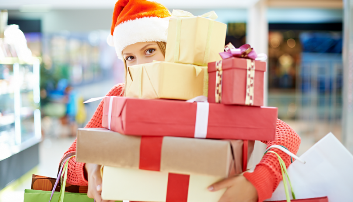 Shopper in a Santa hat holds holiday gifts at a Wisconsin mall, highlighting local holiday spirit for Advisors Management Group.