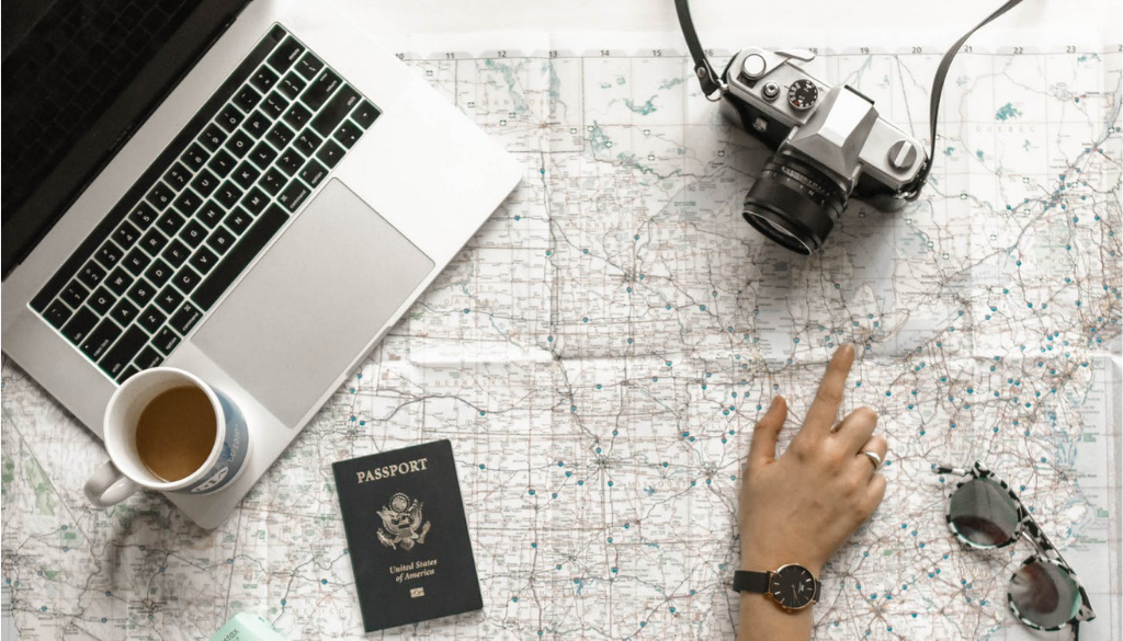 A hand points at a map next to financial planning materials, laptop, and coffee cup—reflecting fiduciary advice in Wisconsin.