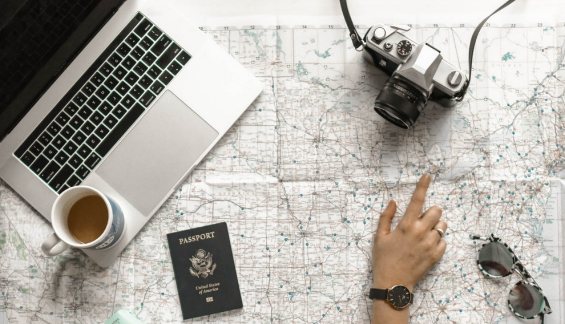 A hand points at a map next to financial planning materials, laptop, and coffee cup—reflecting fiduciary advice in Wisconsin.