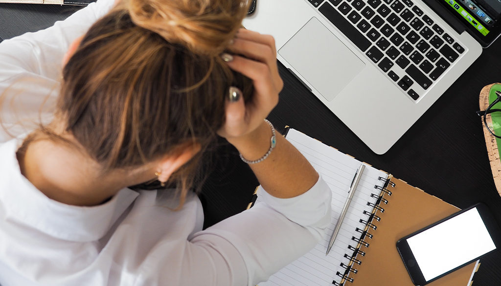 A stressed woman sits at a desk with an open laptop, thinking about tax planning and accounting services in Wisconsin.
