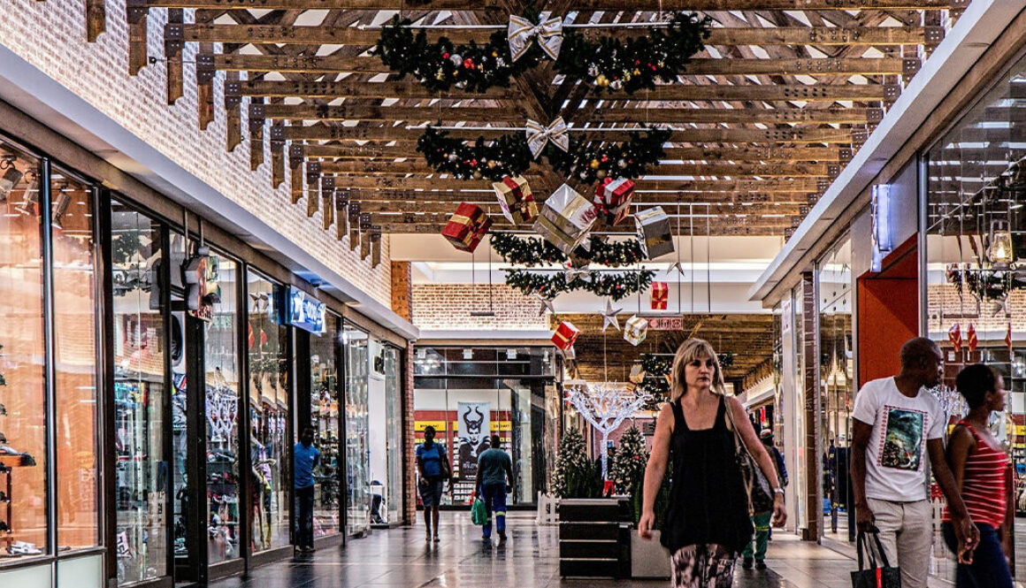 Shoppers walk through a Wisconsin mall adorned with Christmas décor and financial planning displays by fiduciary advisors.