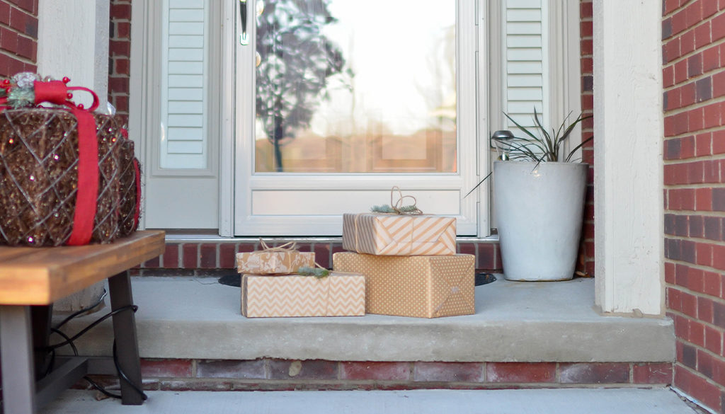 Stacked gift boxes sit by a white door on a Wisconsin porch, reflecting the welcoming spirit of Advisors Management Group.