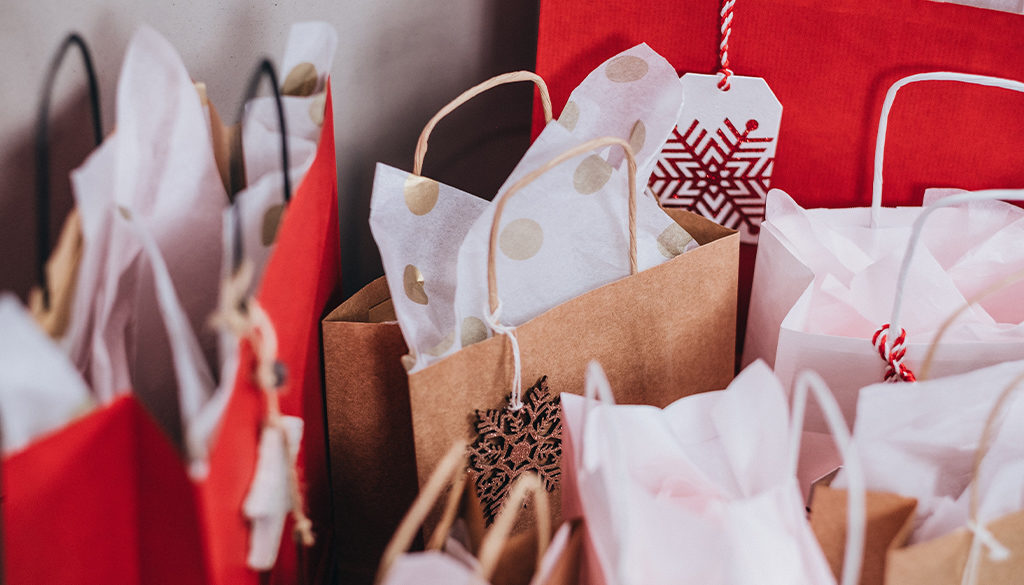 Gift bags with tissue paper and festive tags arranged for Advisors Management Group’s Wisconsin financial planning events.