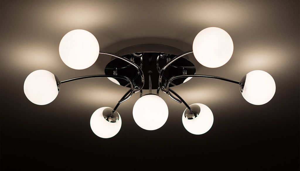 Modern ceiling light fixture with seven glowing bulbs and curved metal arms, illuminating a Wisconsin home office workspace.