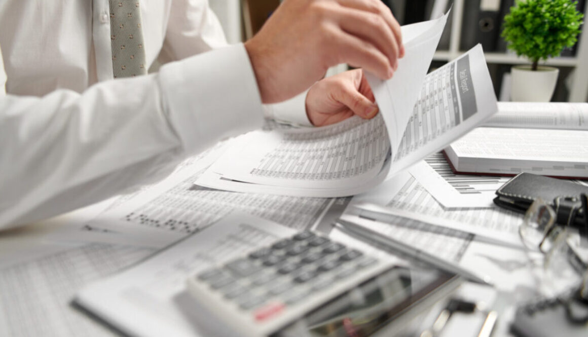 A person reviews financial documents and a calculator at a desk, focusing on tax planning for Advisors Management Group in Wisconsin.