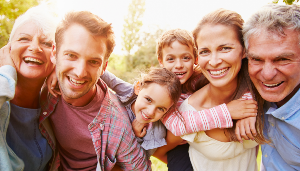 Three generations, including the Sandwich Generation, smile together outdoors—reflecting family financial planning in Wisconsin.