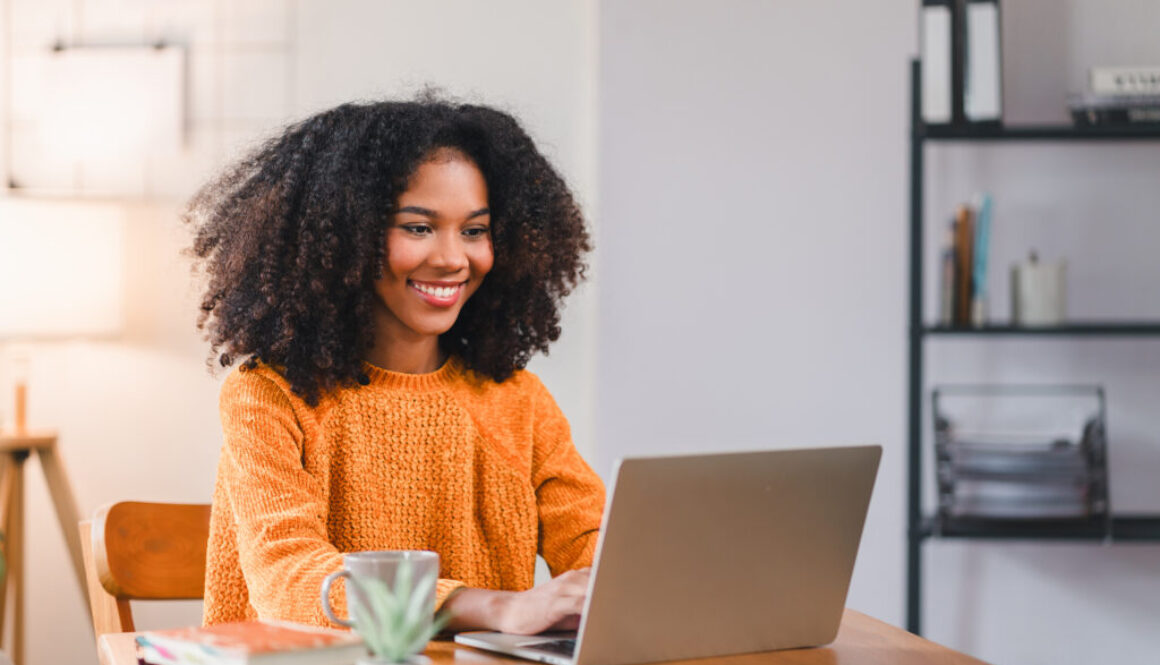 Financial Tips for All Life Stages. Smiling African American woman using a laptop while working from home