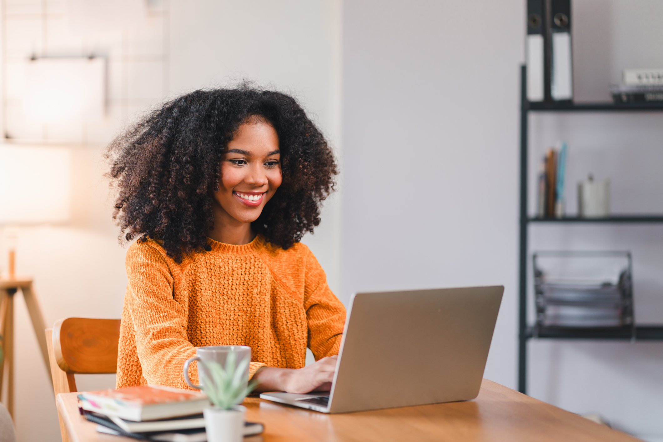 Financial Tips for All Life Stages. Smiling African American woman using a laptop while working from home