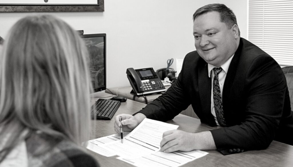 Nathan Deets, Certified Financial Planner (CFP), at Advisors Management Group, smiling while sharing paperwork with clients.