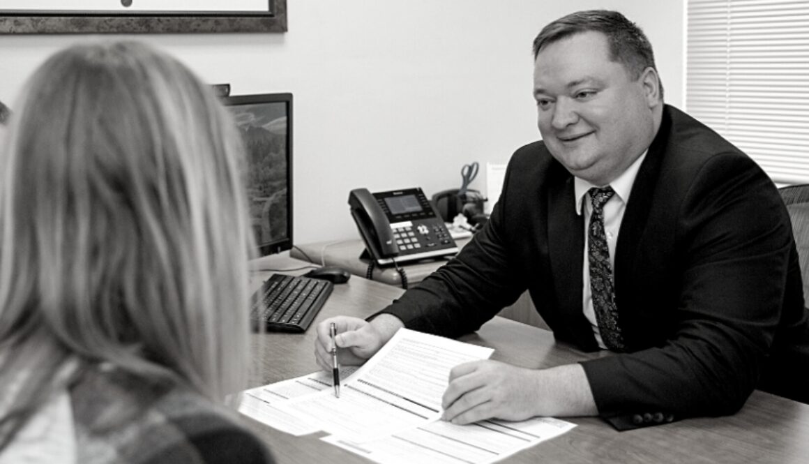 Nathan Deets, Certified Financial Planner (CFP), at Advisors Management Group, smiling while sharing paperwork with clients.