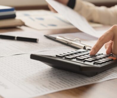 Person reviewing tax documents while punching numbers into a calculator.