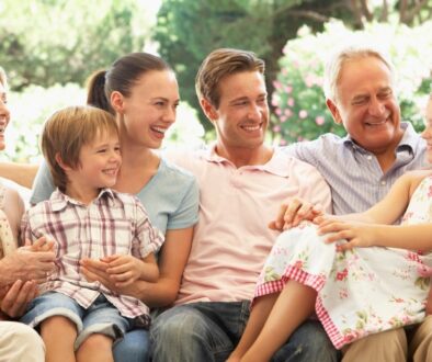 A family sitting on an outdoor patio with grandparents, parents, and grandchildren, laughing.