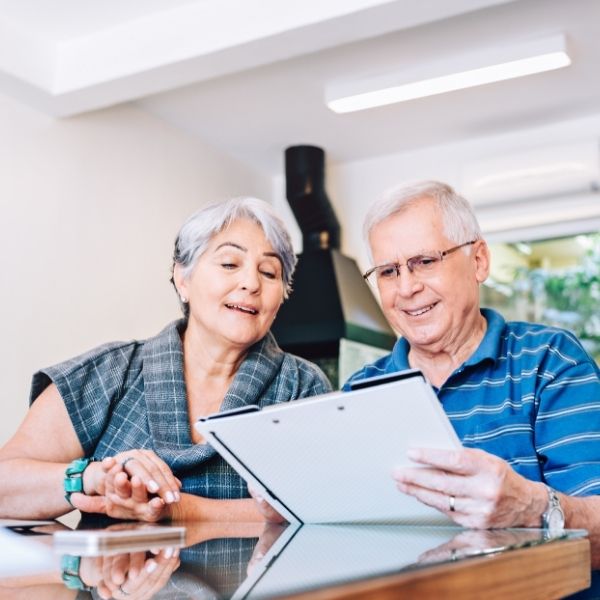A smiling older couple in Wisconsin reviews tax planning documents together at home with help from fiduciary financial advisors.
