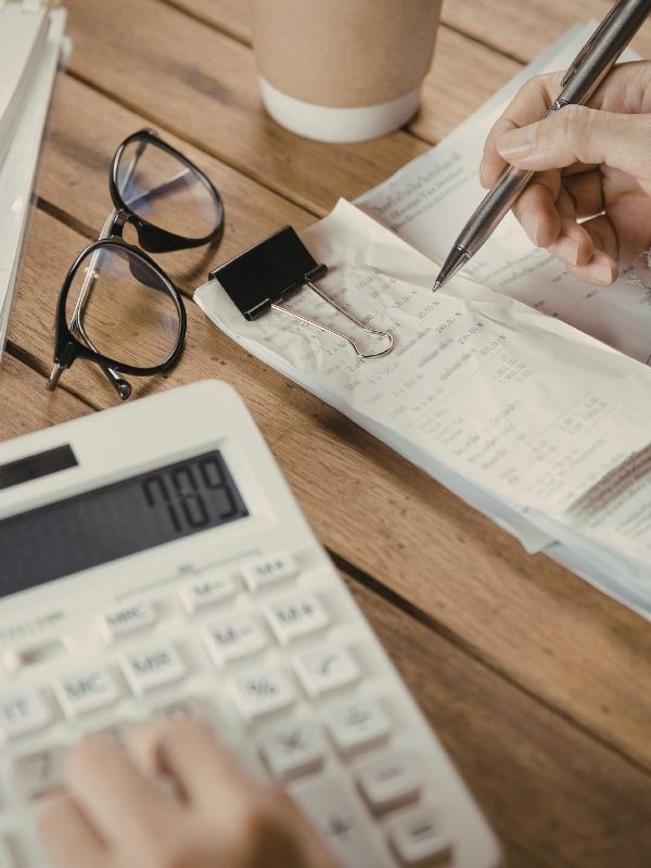 A calculator, receipts, glasses, and coffee cup on a desk represent financial planning by fiduciary advisors in Wisconsin.