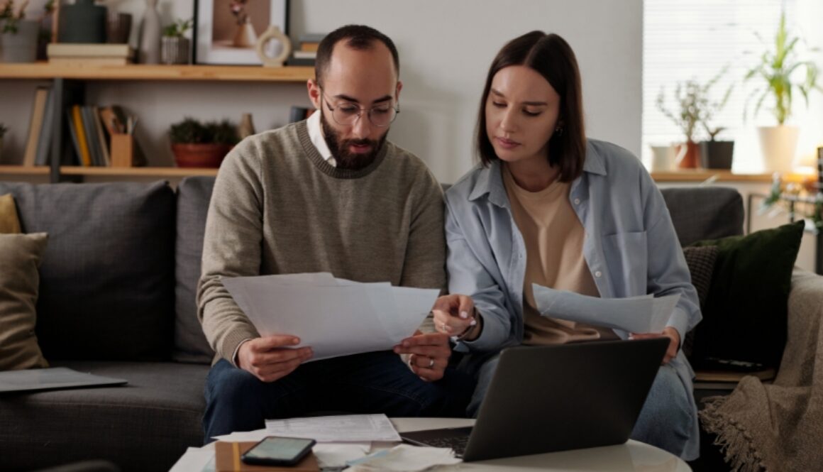 A couple reviewing paperwork while sitting on a couch.