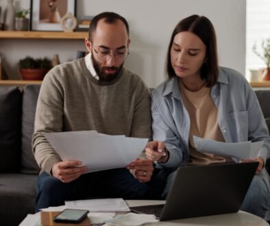 A couple reviewing paperwork while sitting on a couch.