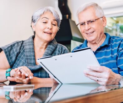 Elderly couple reviewing paperwork at kitchen table.