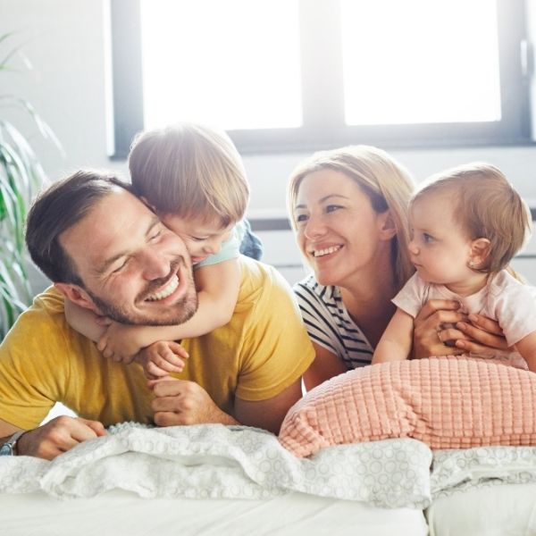 A smiling family of four with two young children relaxes in a sunlit Wisconsin home, reflecting financial peace of mind.