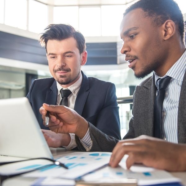 Two fiduciary financial advisors review financial planning charts on a laptop at a desk in Wisconsin.