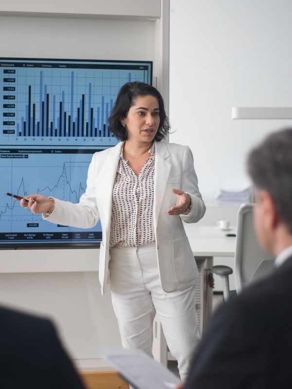 A fiduciary financial advisor in a white suit presents bar and line graphs on financial planning for Advisors Management Group in Wisconsin.