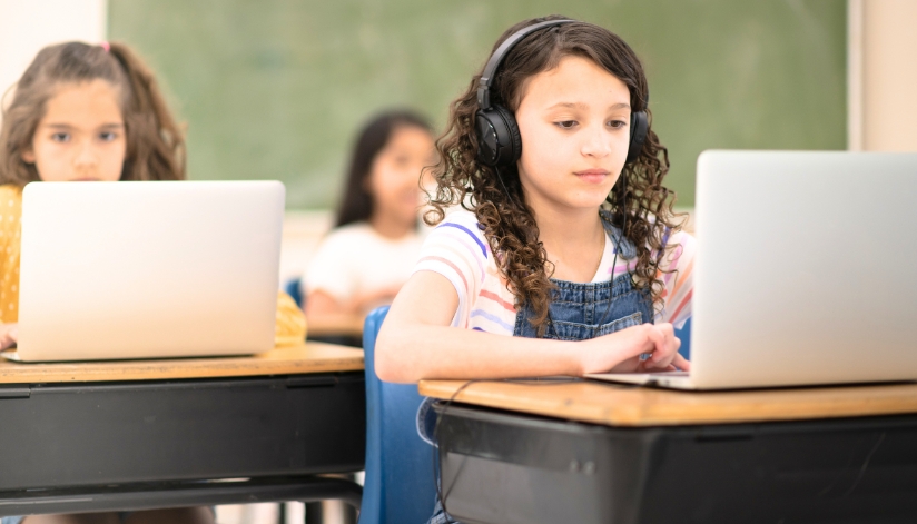 Children in a school classroom working on laptops.