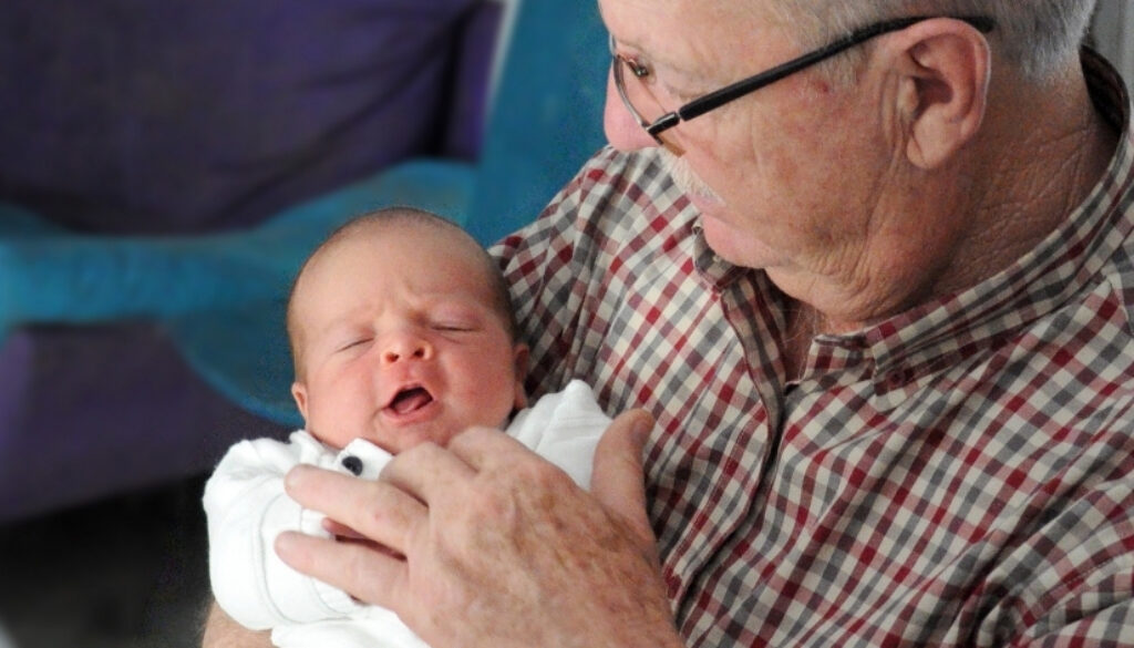 A grandfather holds his newborn grandchild.
