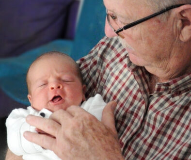 A grandfather holds his newborn grandchild.