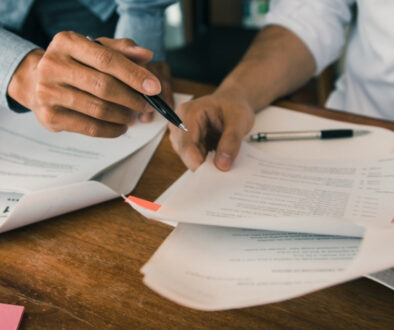People dressed in business casual clothing holding pens and reviewing paperwork.